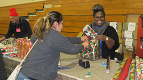 Picture of volunteers having a good time while wrapping presents during the holidays.