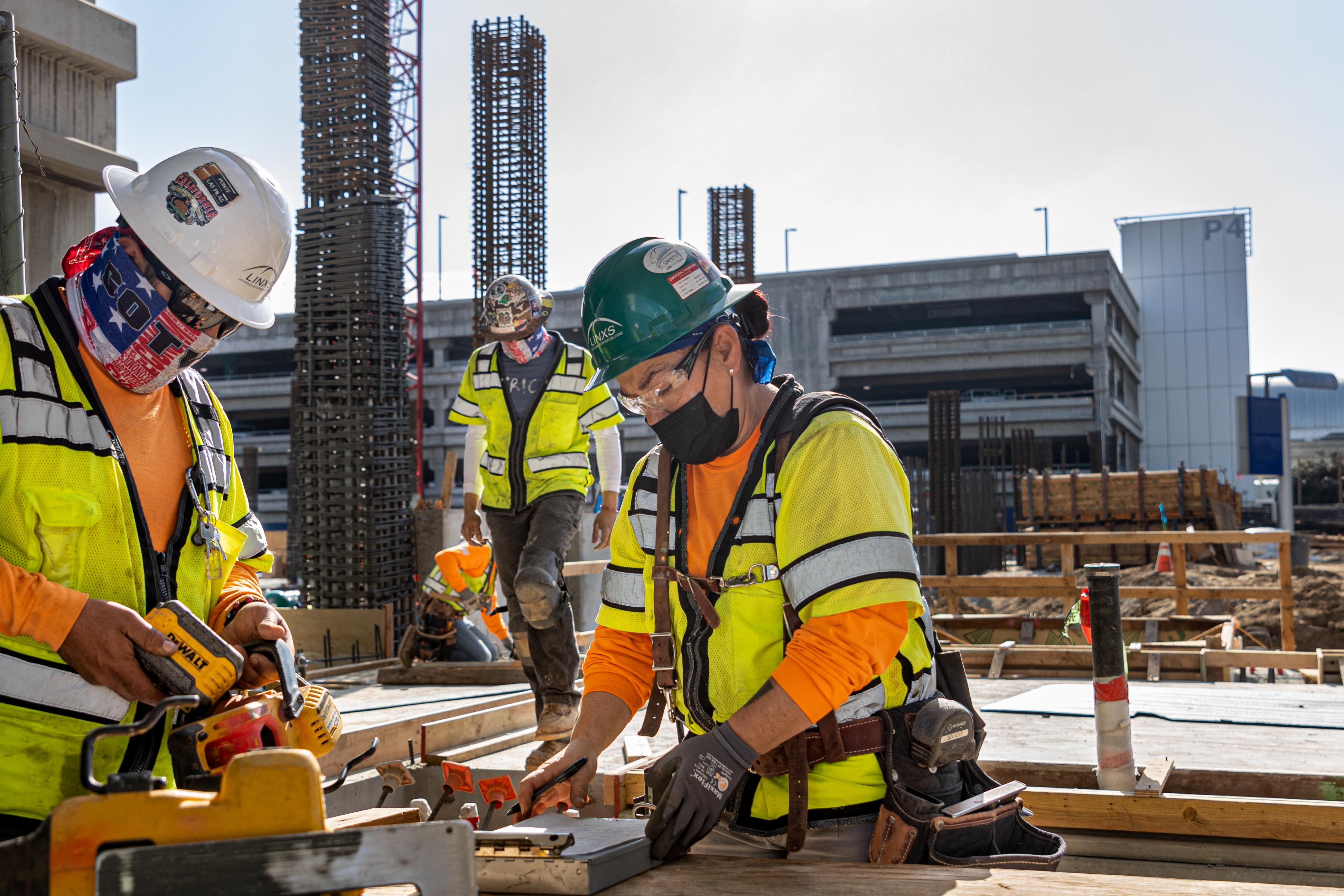 Workers verify and record measurements as part of regular quality checks.